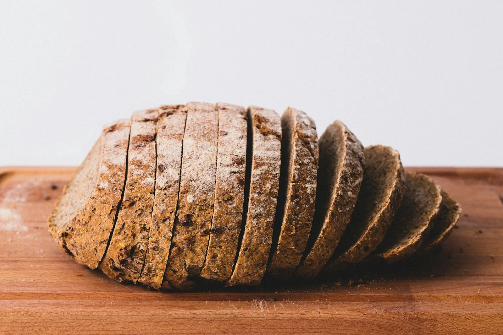 A sliced loaf of brown bread on a wooden board